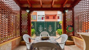 An outdoor patio with a table and chairs, a decorative bowl, and a view of a building with a green gate. - 2348 Villino Mareluce by Barbarhouse (Porto Cesareo)