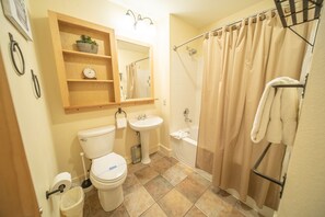 A bathroom with a toilet, sink, and shower. There is a shelf with a plant and a clock. - Silver Mill 8284 (Keystone)