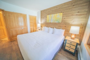 A bedroom with a large bed, wooden headboard, and a nightstand with a lamp. - Silver Mill 8284 (Keystone)