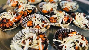 Une assiette remplie de différents plats, probablement des tacos, recouverts de fromage râpé, est posée à l’extérieur, sous le ciel nocturne.