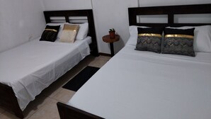 Two single beds with white linens and dark wooden headboards in a room with white walls. - Limon's house in Limon center Costa Rica (Limón)