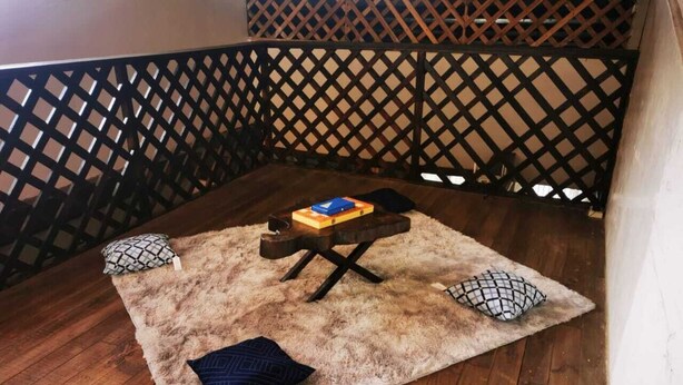 A small, cozy seating area with a wooden table, a fluffy rug, and patterned cushions. - Limon's house in Limon center Costa Rica (Limón)