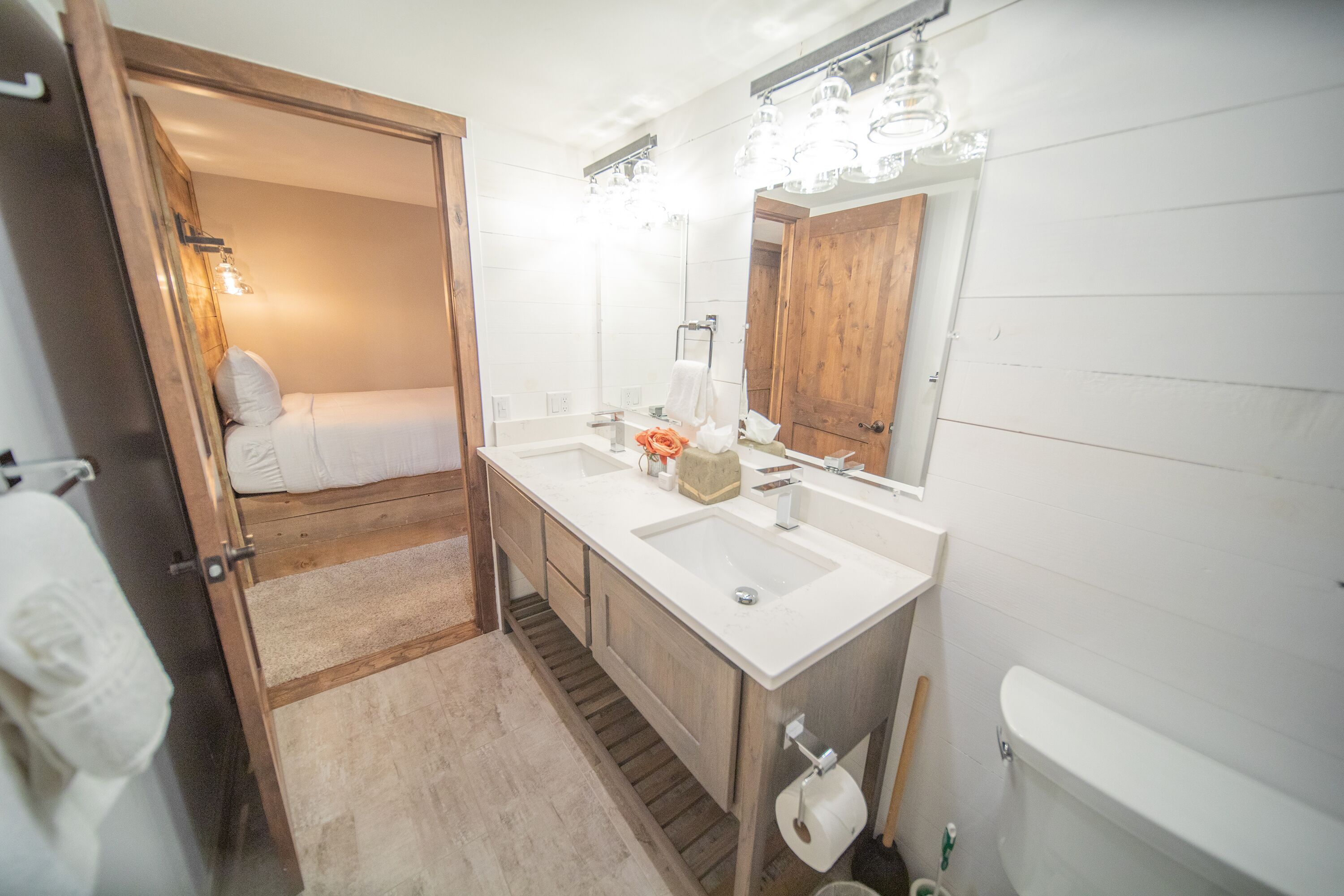 A bathroom with a double sink, wooden vanity, and a large mirror.