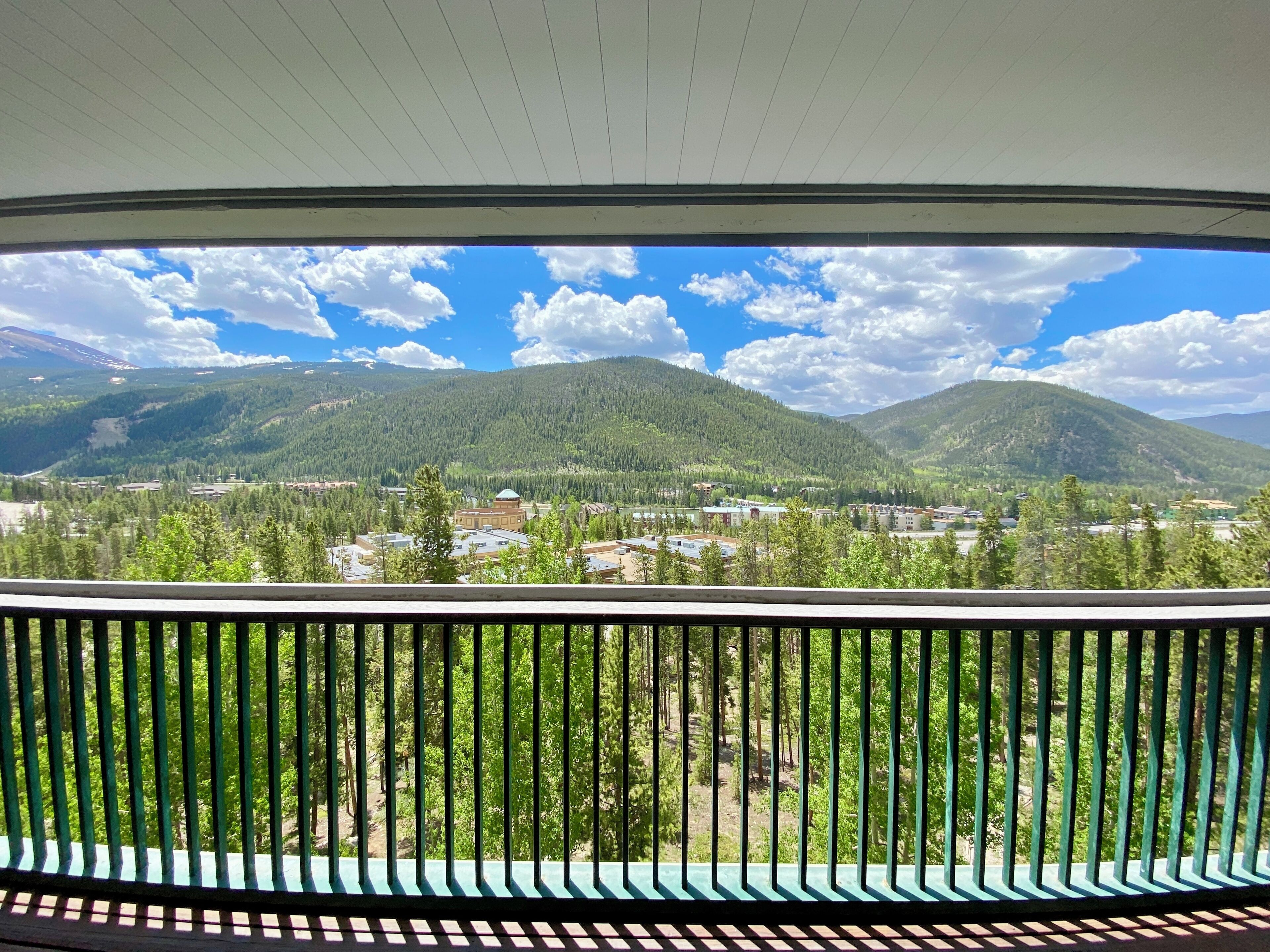 Un balcone con vista su una città circondata da montagne e alberi.