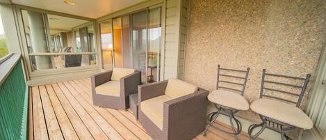 A wooden deck with wicker furniture and a stone wall.