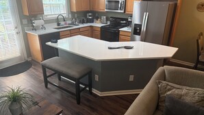Una cocina moderna con una isla grande, armarios de madera, un refrigerador de acero inoxidable y un microondas integrado.