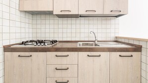 A kitchen with light wood cabinets, a stainless steel sink, and a gas stove. - 2762 Zeus Apartments - Appartamento by Barbarhouse (Porto Cesareo)