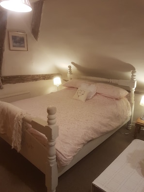 A bedroom with a bed, bedside lamps, a nightstand, and a picture on the wall.