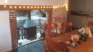 Een gezellig eetgedeelte met een open haard van baksteen, sfeerverlichting en een tafel gedekt voor twee personen.