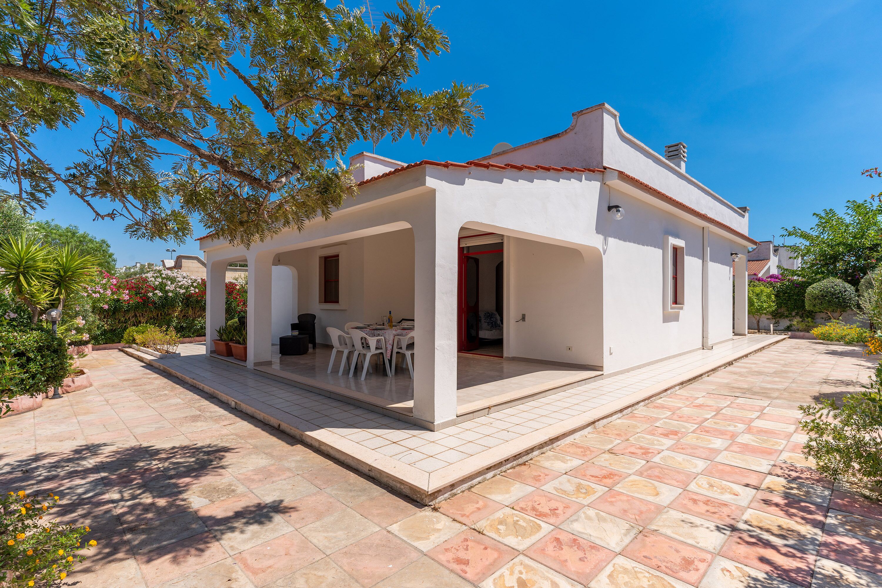 A white house with a tiled patio and a covered outdoor seating area.