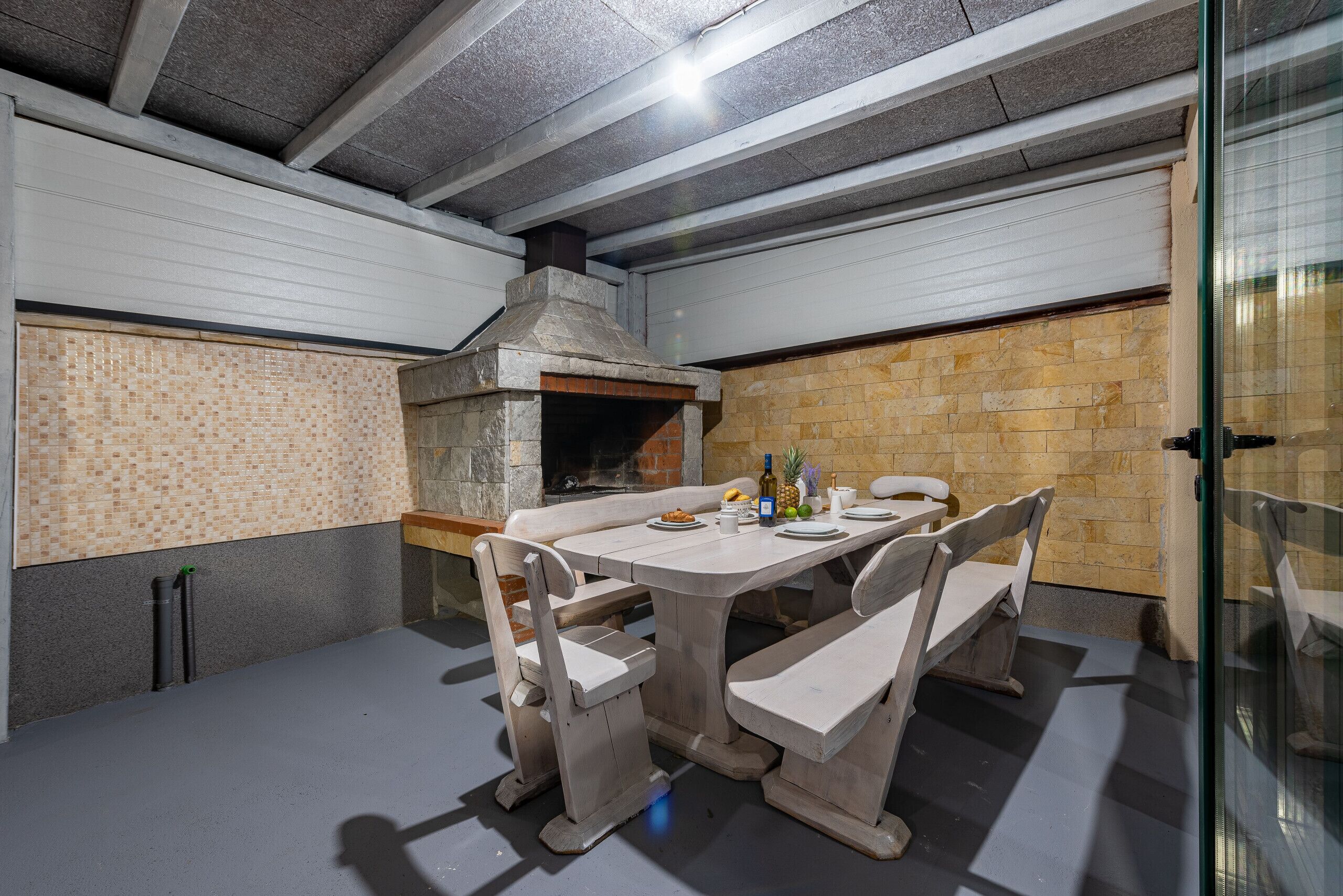 A stone fireplace, a dining table with benches, and a tiled backsplash.