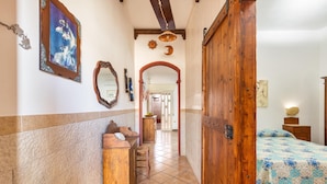 A hallway with a wooden door, a bed with a patterned bedspread, a wooden bench, and a mirror on the wall. - 2669 Casa Ulbia by Barbarhouse (Manduria)