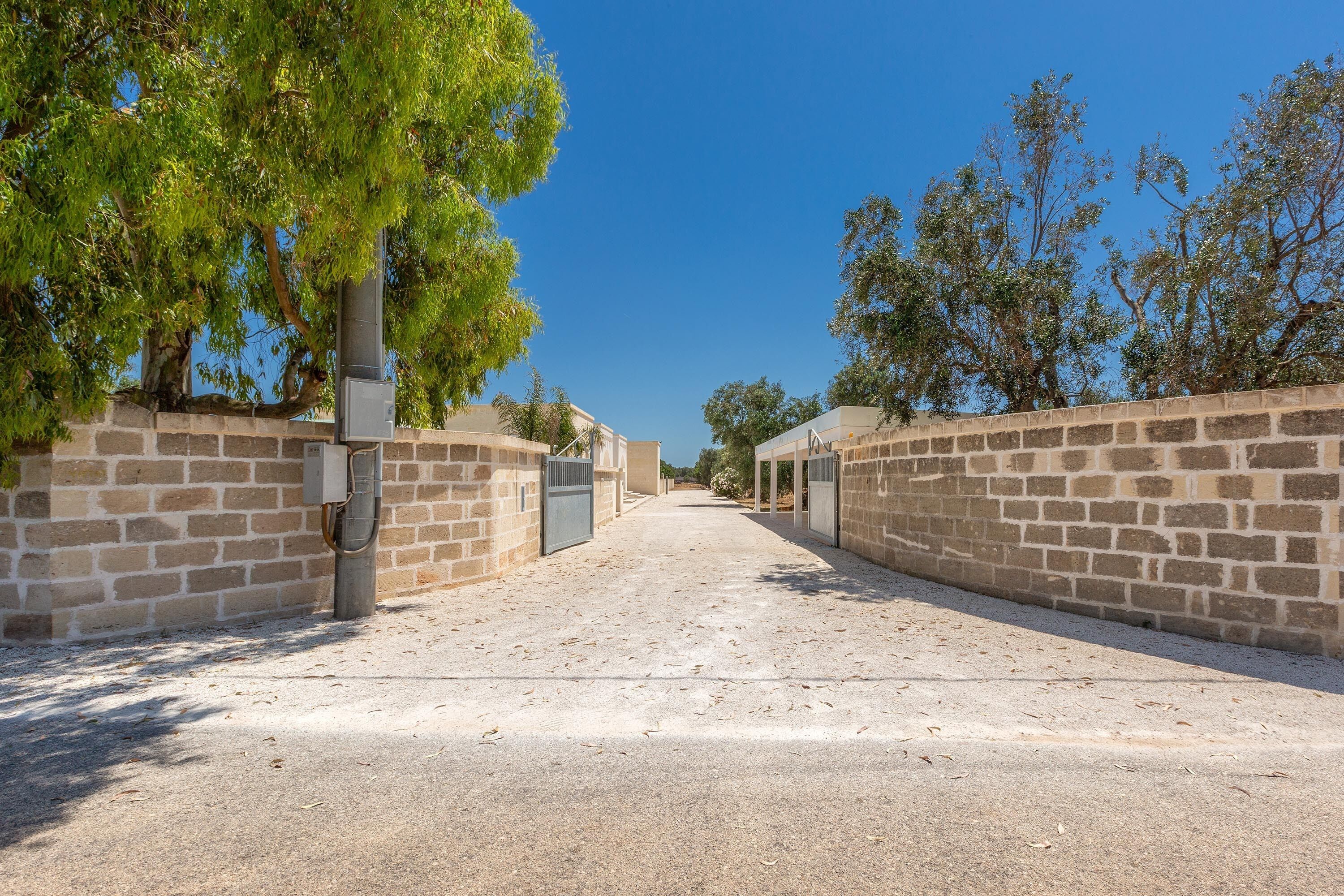 Un sendero pavimentado bordeado por muros de piedra, que conduce a un edificio con acceso cubierto.