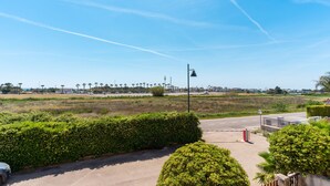 A clear view of a road with a guardrail, a red traffic light, and a distant view of a city skyline with palm trees. - 2991 Villino Patrizia by Barbarhouse (Porto Cesareo)