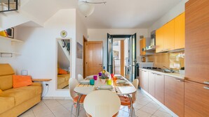 A modern kitchen with wooden cabinets, a dining table set for four, and a sofa in the living area. - 2991 Villino Patrizia by Barbarhouse (Porto Cesareo)