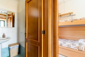A bathroom with a wooden door, a sink, and a small trash bin. - 2991 Villino Patrizia by Barbarhouse (Porto Cesareo)