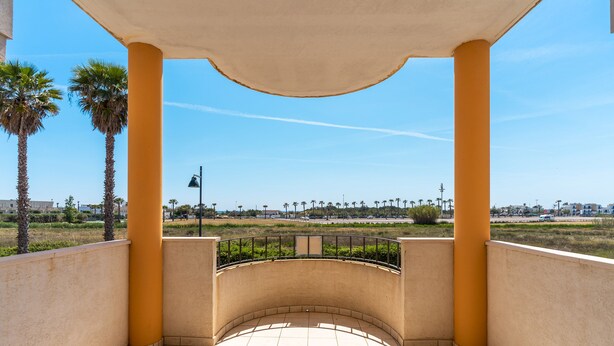 A covered outdoor area with a tiled floor, palm trees, and a view of a distant landscape. - 2991 Villino Patrizia by Barbarhouse (Porto Cesareo)