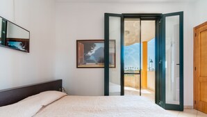A bedroom with a bed, a framed picture, a sliding glass door, and a wooden door. - 2991 Villino Patrizia by Barbarhouse (Porto Cesareo)