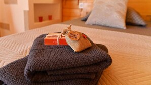 Een net opgemaakt bed met een opgevouwen deken, een klein label en twee zeepjes.