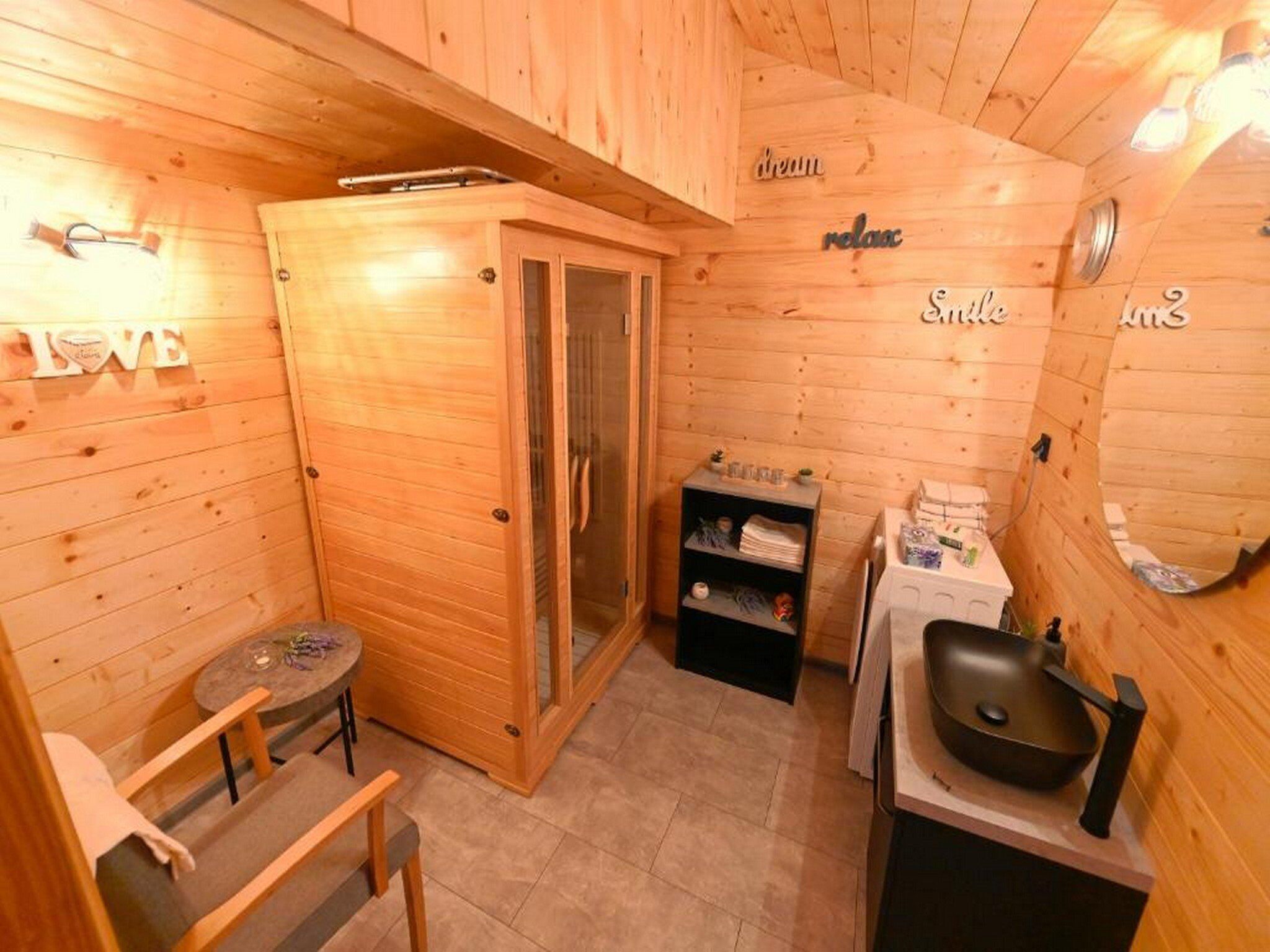 A wooden cabin with a sauna, a small table with chairs, and a sink.