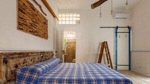 Een slaapkamer met een bed, houten hoofdbord en een raam met uitzicht.