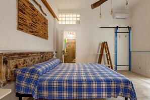 Quarto com cama, cabeceira de madeira e janela com vista.