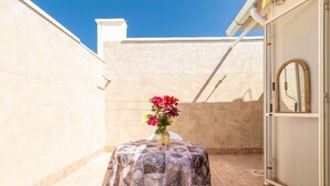 A small patio with a table covered by a patterned tablecloth, a vase with flowers, and a white chair. - 3021 Villa Seremar by Barbarhouse (Trepuzzi)