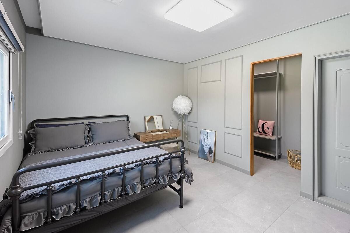 A bedroom with a bed, bedside table, wardrobe, and a mirror.