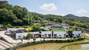 Un quartier résidentiel avec des maisons modernes, un mur en pierre et un petit étang.