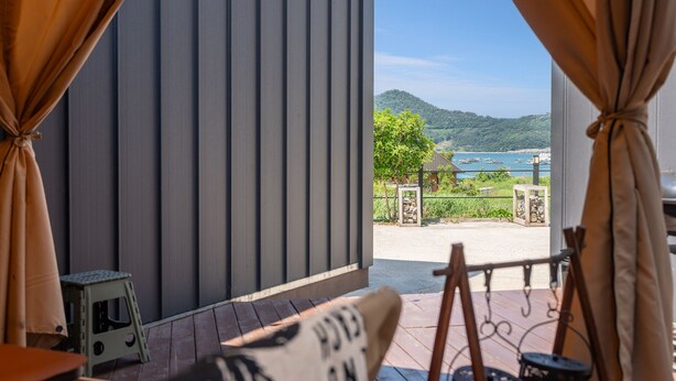 Une pièce offrant une vue sur un paysage côtier, avec une terrasse en bois et une petite table.