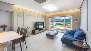 Un salon moderne avec un téléviseur, un canapé et un coin repas.