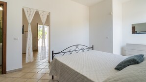A bedroom with a bed, a nightstand, and a mirror on the wall. - 2952 Residence Flamingo - Appartamento Piccolo by Barbarhouse (Manduria)