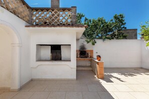 A patio with a built-in grill, a small seating area, and a view of the surrounding area. - (Manduria)