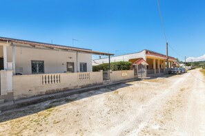 Una calle residencial con casas, un camino de tierra y automóviles estacionados.