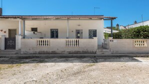 A two-story building with a tiled roof, a balcony with a balustrade, and a gated entrance.