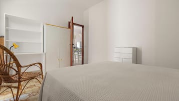 Un dormitorio con cama, una silla, un armario y un espejo.