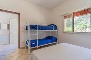 A room with a bunk bed, a single bed, a door, and a window with blinds. - 2953 Residence Flamingo - Appartamento Medio by Barbarhouse (Manduria)