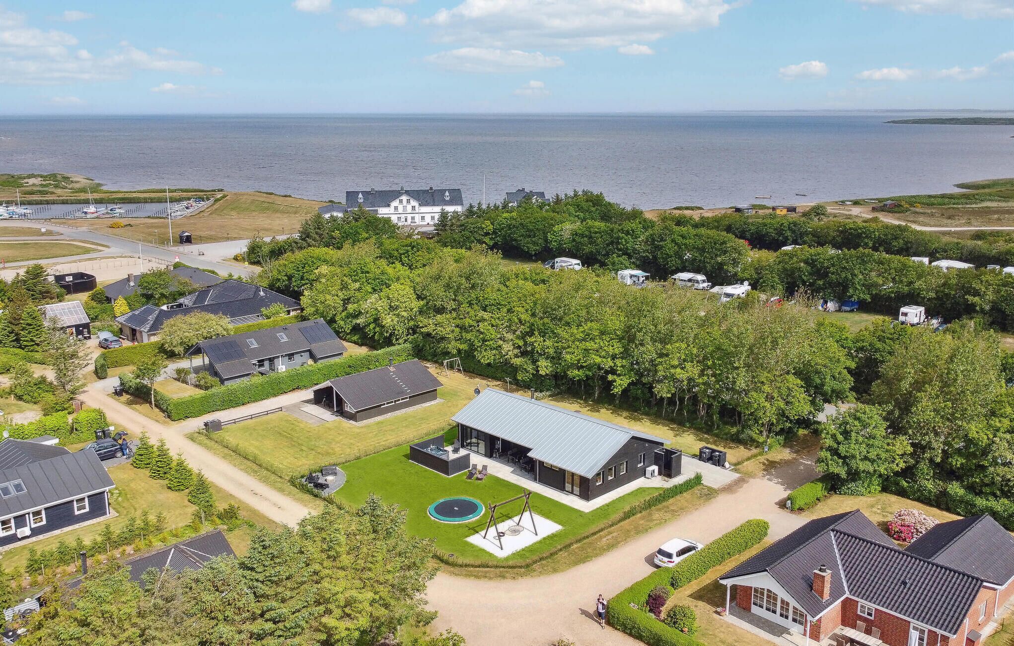 Et boligområde med huse, en swimmingpool og udsigt til havet.