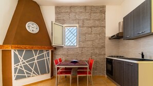 A kitchen with a dining table, chairs, a clock, a window, and cabinets. - 3047 Villetta Nicols by Barbarhouse (Torricella)