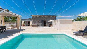 A swimming pool with a pergola and lounge chairs, a building with a stone facade, and a clear blue sky. - 3047 Villetta Nicols by Barbarhouse (Torricella)