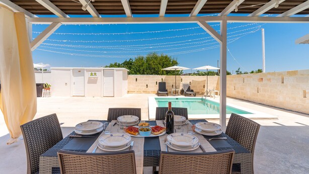 An outdoor dining area with a pool in the background. - 3047 Villetta Nicols by Barbarhouse (Torricella)