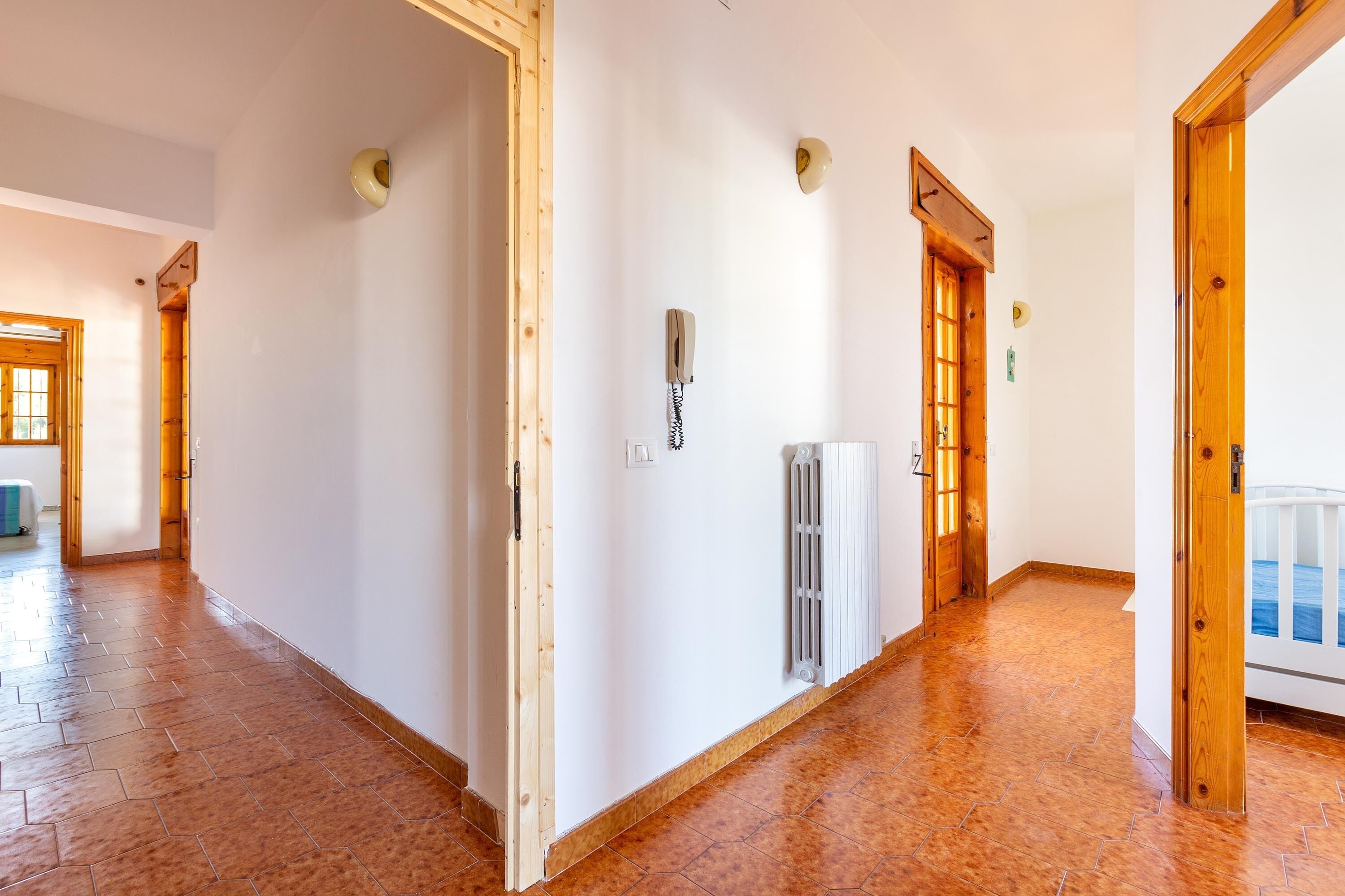 A hallway with wooden doors, a radiator, and a telephone.
