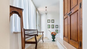 A hallway with a wooden bench, a vase with flowers, and a wooden door.