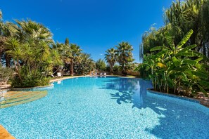 A clear blue swimming pool surrounded by palm trees and tropical plants. - 3122 Villa Torre Bianca by Perle di Puglia (Manduria)
