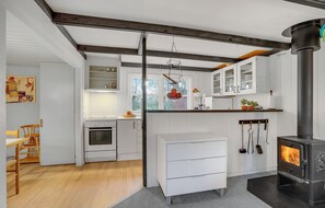 Une cuisine moderne avec des meubles blancs, un four encastré, une cuisinière et un panier à fruits suspendu.