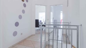 A hallway with a staircase, white walls, and a tiled floor. - Holiday apartment with sea views, air conditioning and pool (Karlobag)