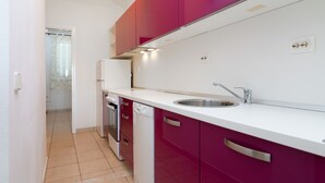 A modern kitchen with white countertops, a stainless steel sink, and red cabinets. - Holiday apartment with sea views, air conditioning and pool (Karlobag)