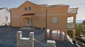 A two-story building with a balcony and a view of the sea.