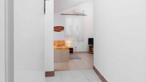 Una habitación de hotel moderna con una cama, televisión, escritorio y ventana con cortinas.
