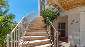 A spiral staircase with white railings leading to a wooden door.